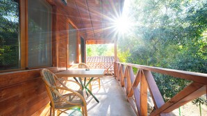 A wooden deck with a table and chairs, overlooking a garden. - Welt bungslows  (Konyaalti)