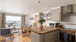 Een moderne keuken met houten vloeren, een centraal eiland en uitzicht naar buiten.