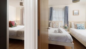 Een hotelkamer met twee bedden, een houten deur en een raam met gordijnen.