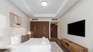 A modern hotel room with a large bed, a TV mounted on the wall, and a wooden console table. - Prime 2BR Downtown Iconic Burj View (Dubai)