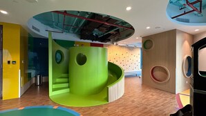 A modern interior with a green spiral slide, wooden flooring, and a circular ceiling feature. - Prime 2BR Downtown Iconic Burj View (Dubai)