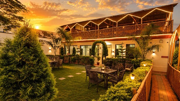A courtyard with a dining area, outdoor seating, and a covered structure with lighting. - Hotel Happy Forest - Boutique Garden Retreat in Mount Abu (Mount Abu)