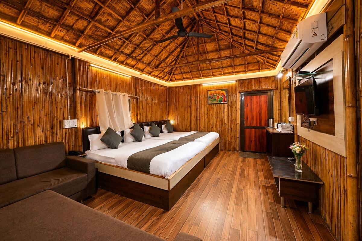 A room with a bed, a sofa, a TV, and a wooden ceiling.