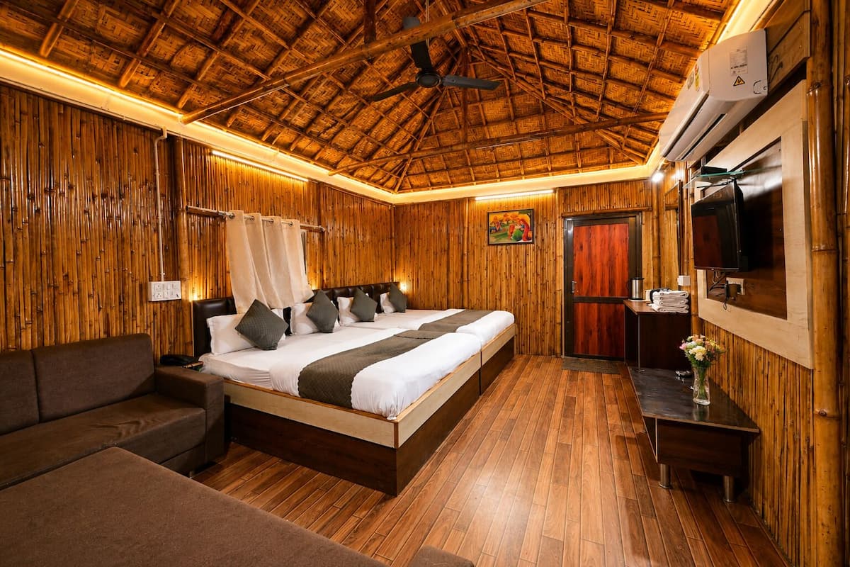 A room with a bed, a sofa, a TV, and a wooden ceiling.