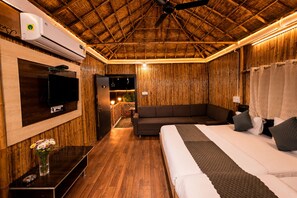 A room with a bed, a sofa, a TV, and a ceiling fan. - Hotel Happy Forest Inn (Mount Abu)