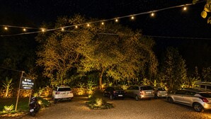 A hotel entrance at night with string lights, parked cars, and a sign indicating 'Hotel Happy Forest Inn.' - Hotel Happy Forest - Boutique Garden Retreat in Mount Abu (Mount Abu)