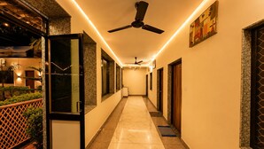 A hotel corridor with a ceiling fan, doors, and a view of the outdoors. - Hotel Happy Forest - Boutique Garden Retreat in Mount Abu (Mount Abu)