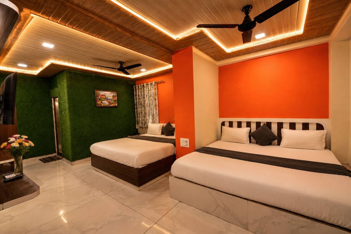 A hotel room with two beds, a green accent wall, a ceiling fan, and a painting.