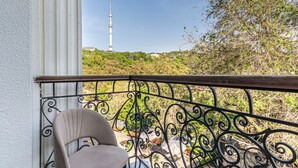 Een balkon met een metalen hekwerk, een stoel en een toren in de verte.