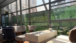 Een modern interieur met een marmeren receptiebalie, geruite stoelen en uitzicht op groen door grote ramen.