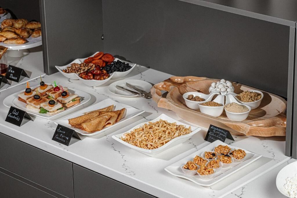 Un buffet con diversi cibi tra cui panini, pasticcini e frutta.