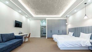 Een moderne hotelkamer met een flatscreen televisie, een bank, een bureau, een bed met witte lakens en een kledingkast.