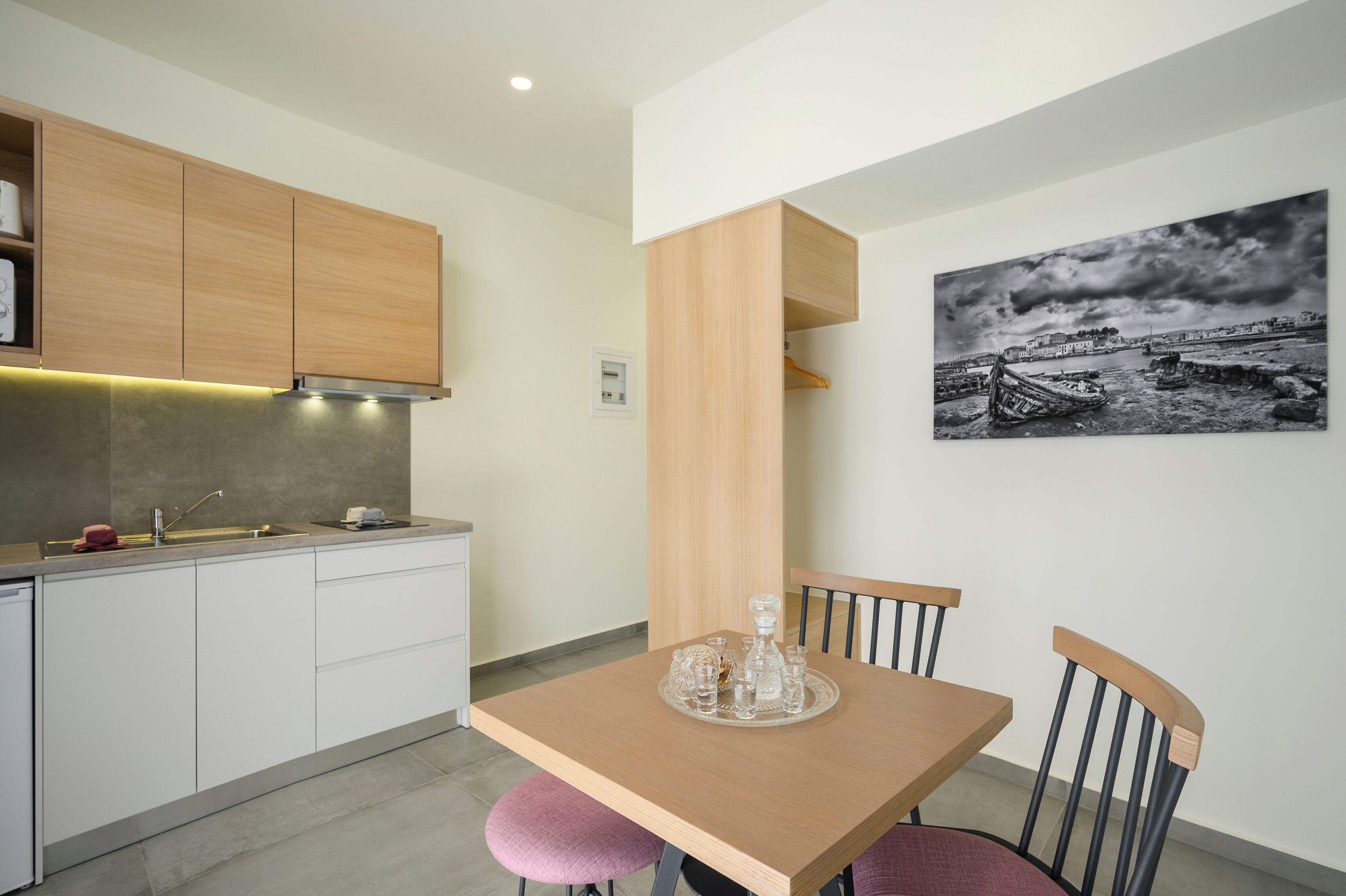 Una cocina moderna con armarios de madera, horno empotrado y comedor con mesa y sillas.