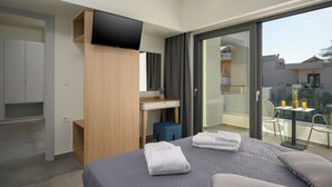 Una habitación de hotel moderna con cama, escritorio, televisión y balcón con mesa y sillas.