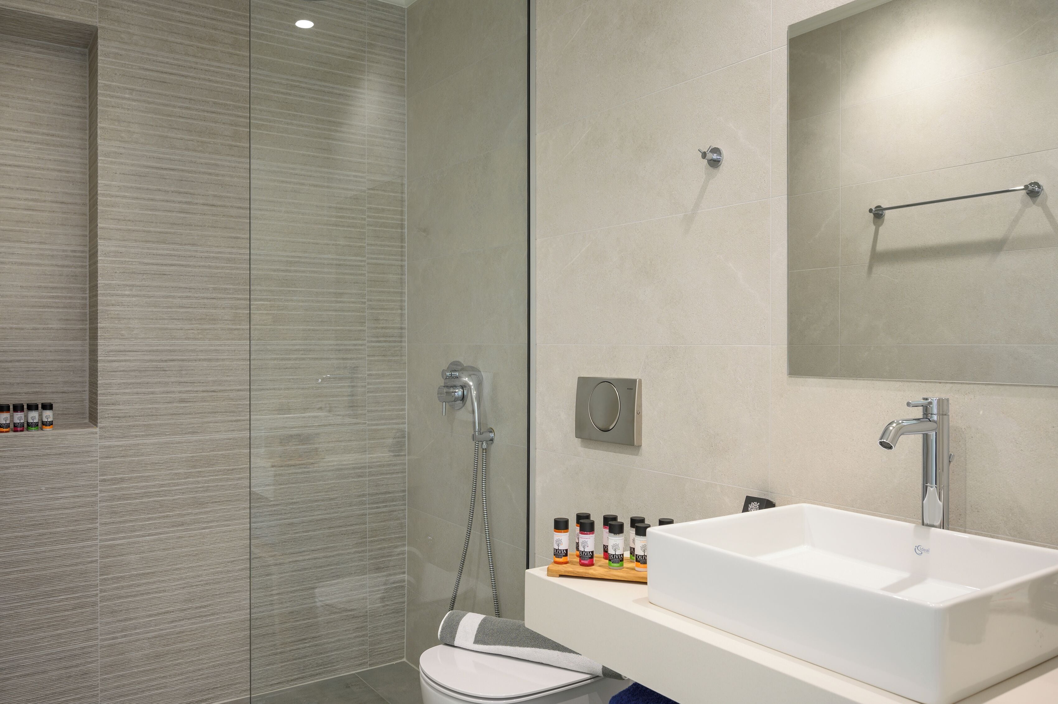 A modern bathroom with a large white sink, a handheld showerhead, and a glass-enclosed shower.