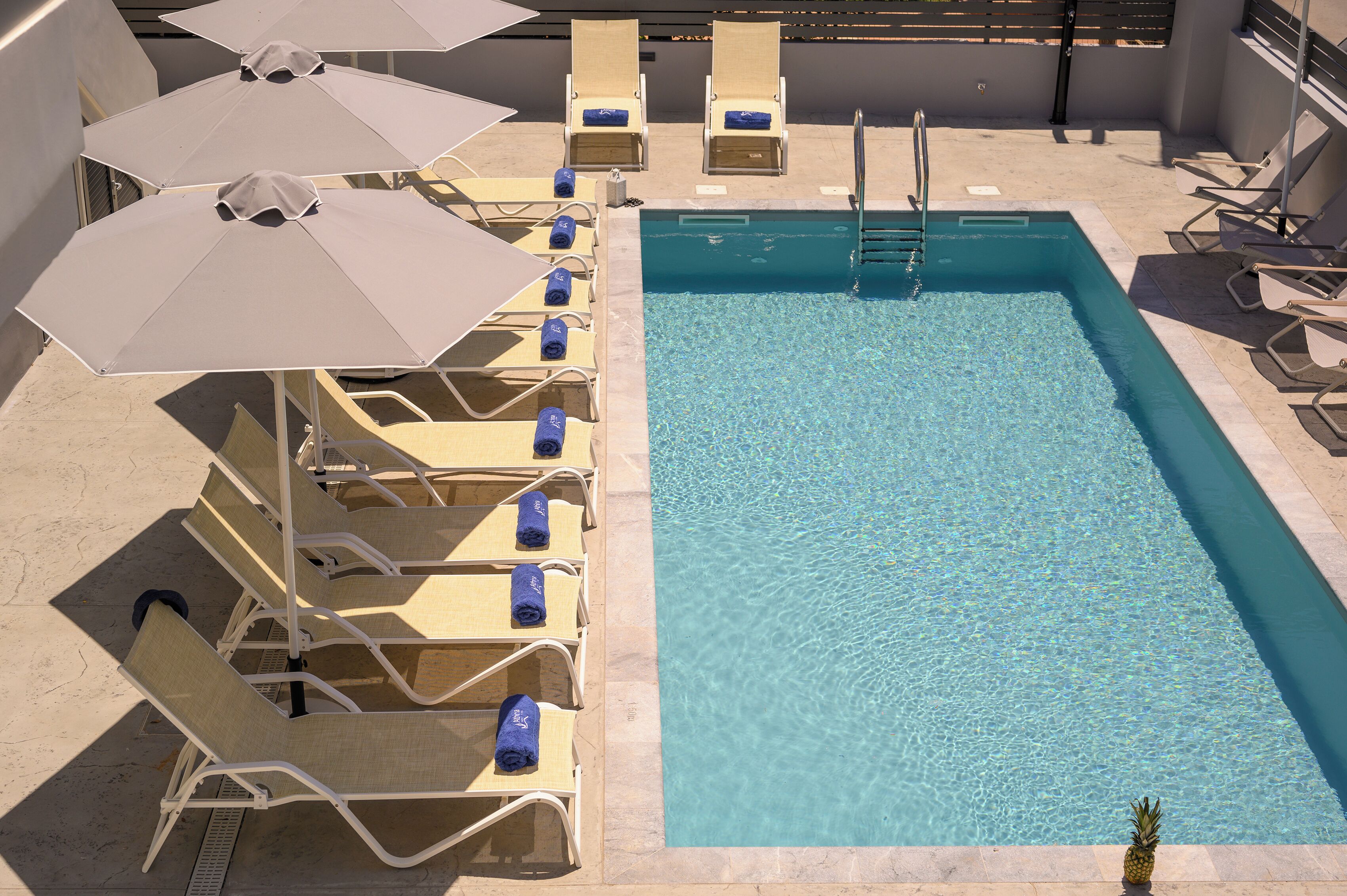 Un espace piscine équipé de chaises longues et de parasols.