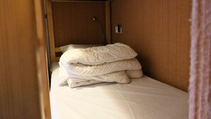 Ein kleines, kompaktes Zimmer mit einem Etagenbett, einem Einzelbett und einem kleinen Tisch.