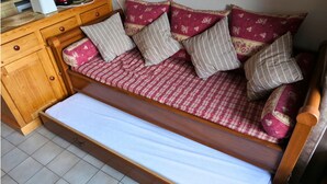 Ein hölzernes Bett mit einer Matratze, Kissen und einer Decke.
