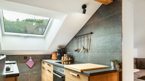 A kitchen with a skylight, wooden cabinets, a countertop, and a hanging utensil rack. - Apartment "Rachel" with Mountain View, Shared Terrace and Wi-Fi (Perlesreut)