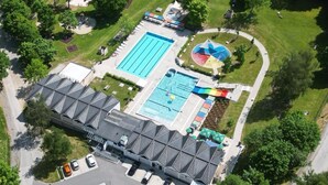 An aerial view of a hotel with a swimming pool, a children's play area, and a parking lot. - Apartment "Rachel" with Mountain View, Shared Terrace and Wi-Fi (Perlesreut)