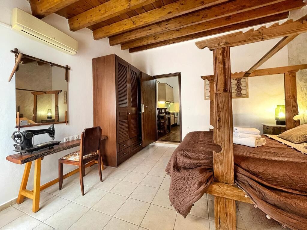 A bedroom with a wooden bed, a sewing machine, and a chair.