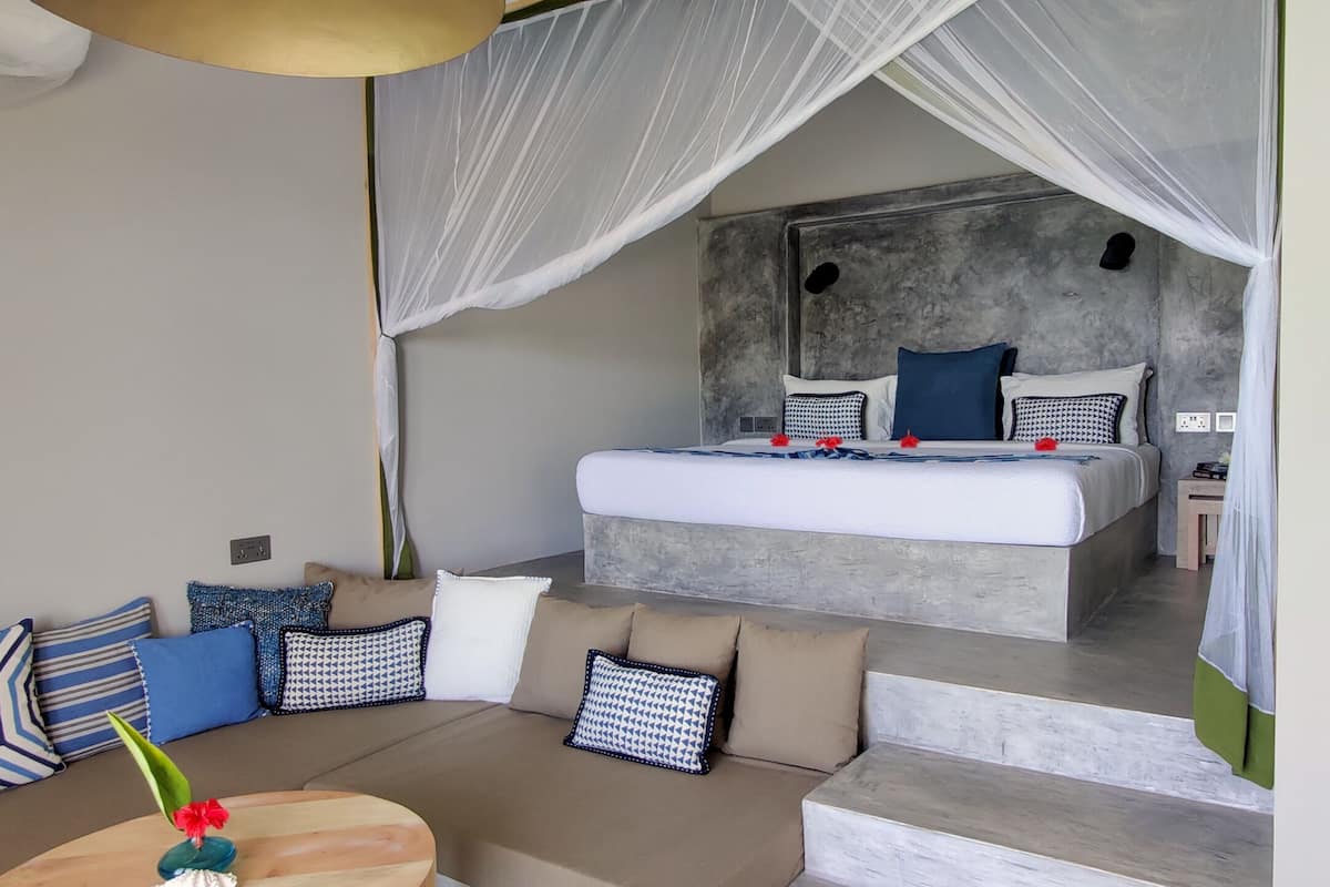 A modern bedroom with a large bed, a sofa, and a small table with a vase.