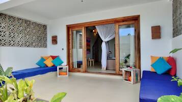 Una habitación con un sofá azul, una puerta corredera con marco de madera y un papel tapiz estampado.