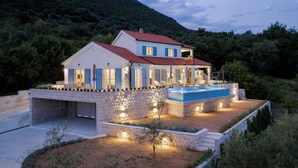 A two-story house with a swimming pool, surrounded by a landscaped garden and a mountain backdrop. - Luxury 4-bedroom Villa with Private Heated Pool & Sea View, near Portonovi. (Đenovići)
