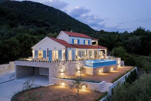 A two-story house with a swimming pool, surrounded by a landscaped garden and a mountain backdrop. - Luxury 4-bedroom Villa with Private Heated Pool & Sea View, near Portonovi. (Đenovići)