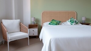 Un dormitorio con cama, una silla, una mesita de noche y una lámpara.