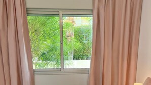 Una camera da letto con un letto, una finestra, tende e un comodino con una lampada.