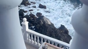 Un balcone con vista sull'oceano, ringhiere bianche e una statua.