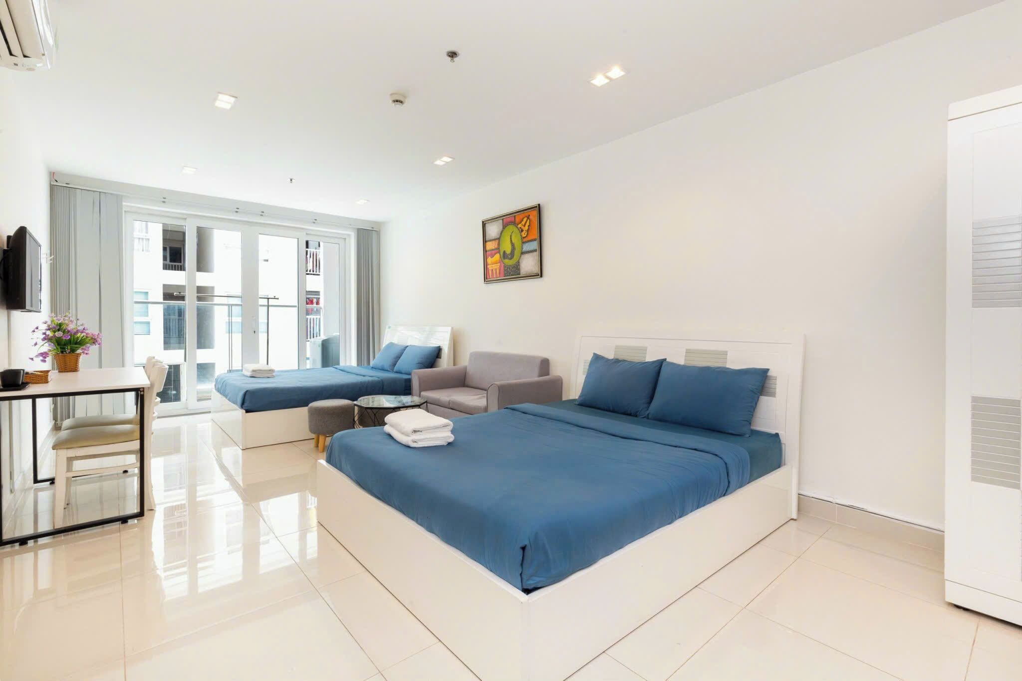 A modern hotel room with a large bed, a sofa, a small table, and a TV.
