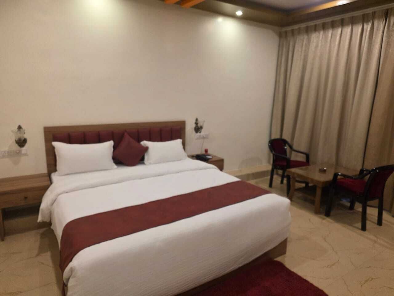 A hotel room with a large bed, a desk, and two chairs.