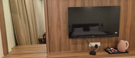 Ein Holz-Entertainment-Möbel mit einem Flachbildfernseher, einer Steckleiste und einem rosa Wasserkocher.