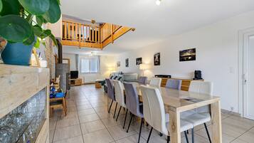 A spacious dining area with a high wooden ceiling and a view of the kitchen below.