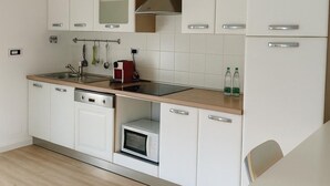 A modern kitchen with white cabinets, a stainless steel sink, a microwave, and a built-in oven. - La Manovella Apartment (Caselle Torinese)