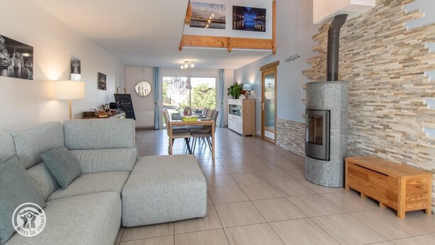 A modern living room with a sofa, a dining area, a fireplace, and a kitchen visible in the background. - Guest Room "Room 2 - Seychelles" with Shared Terrace, Garden, and Wi-Fi (Annecy)