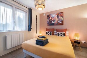 Een moderne slaapkamer met een groot bed, een radiator, een raam met gordijnen, een schilderij van een olifant en twee bedlampjes.