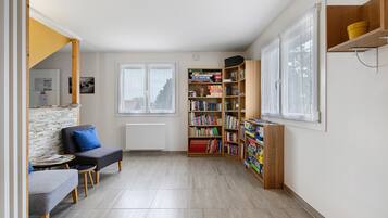 Een knus woongedeelte met een bank, een klein tafeltje, een boekenkast en een radiator.