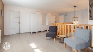Une pièce moderne comprenant un banc en bois, deux fauteuils, une petite table ronde et une armoire.