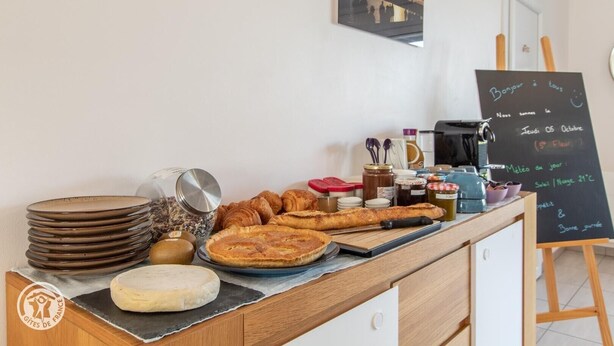 Un buffet de petit-déjeuner proposant des viennoiseries, du fromage et un menu écrit sur un tableau noir.
