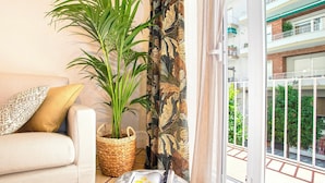 A living room with a sofa, a potted plant, a woven basket, and a magazine on a round ottoman. - Wonderful 5-bedroom Apart in Granada. Recogidas II (Granada)