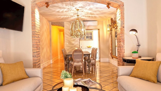 A living room with a sofa, a coffee table with candles, and a dining area with a chandelier. - Wonderful 5-bedroom Apart in Granada. Recogidas II (Granada)