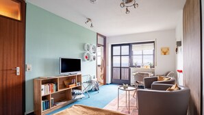 A room with a bed, a television, a bookshelf, a chair, and a window. - Apartment 'Bergluft' with Rhine Valley View, Private Terrace and Wi-Fi (Sasbachwalden)