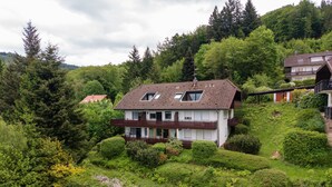 A two-story house with a sloped roof, a balcony, and a garden. - Apartment 'Bergluft' with Rhine Valley View, Private Terrace and Wi-Fi (Sasbachwalden)