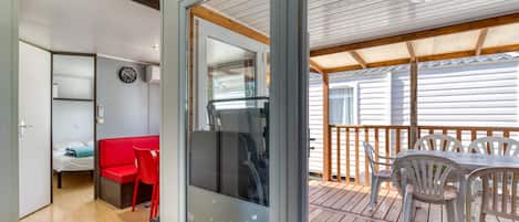 A room with a bed, a red chair, a table, and a balcony with a view.