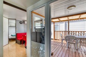 Ein Zimmer mit einem Bett, einem roten Sessel, einem Tisch und einem Balkon mit Aussicht.