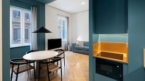 A modern kitchen with a built-in oven, a dining area with a round table and chairs, and a view of a building through a window. - Superior Family Apartment with Wi-Fi and Air Conditioning (Napoli)