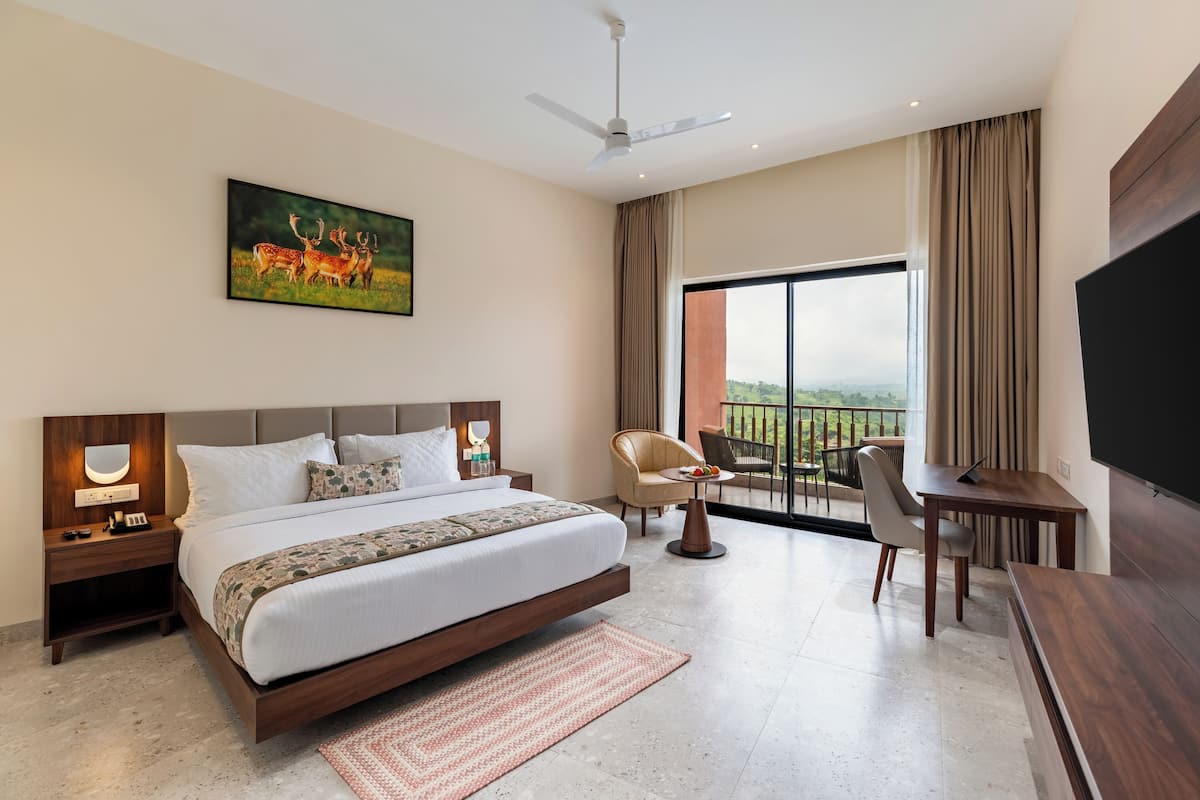 Een moderne hotelkamer met een groot bed, een bureau, een stoel, een televisie, een balkon met uitzicht en een schilderij aan de muur.